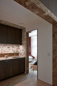 Hnědý kámen byl použit i v dalších místnostech, spolu s dřevem dělá interiér útulným. (Byt Masna, Iva Hájková Studio)