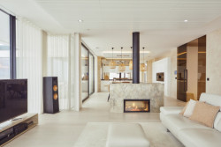 Impozantní krb jemně odděluje ryze odpočinkovou obývací část od jídelního prostoru. (Bungalov ve východních Čechách; Atelier Kunc)