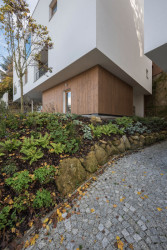 Nové domy jsou tři bílé archetypální hmoty, které se pomyslně vznášejí nad půdorysně menším a materiálově odlišeným spodním podlažím. (Trojdům, Martin Čeněk)