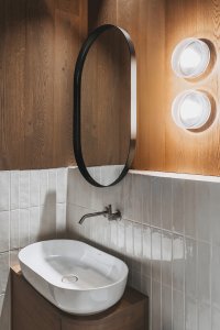 Detaily interiéru pracují s kontrastem tmavého dřeva a světlého keramického obkladu. (Chalupa ve stráni; Mimosa Architekti)