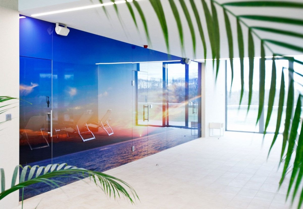 Celoskleněný obklad stěny s integrovanými třemi otočnými dveřmi, materiál Grafosklo – motiv zapadajícího slunce, velikost 8 × 2,5 m - foto