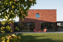 Hravý prvek - kulaté okno do koupelny a na schodiště, které se opakuje i na nábytku. (Cihlový dům v Pardubicích; architekti Jakub Dvořák a Michal Bílek)