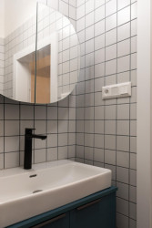 Světle šedý obklad a tmavá spárovačka ladí s černými bateriemi. - Rekonstrukce bytu v Praze Holešovicích, Studio Schwestern.