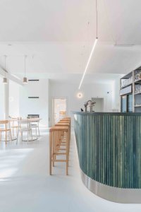 Zelený bar je v kontrastu s okolními neutrálními materiály a barevně tlumeným prostředím. (Interiér restaurace Blatenský dvůr, Dominik Cvrček)