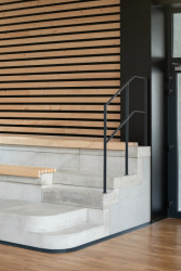 Studené barevné odstíny, přiznané technologie a surové materiály doplňuje teplý dřevěný obklad. (Hala Řevnice, Grido)