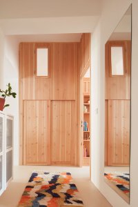 Kumbál na věci a nad ním okénko z dětského pokoje. (Plus One Architects, byt ve Vršovicích)