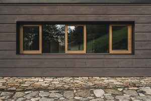 Fasáda pracuje s typickým trojdělením a kamennou podezdívkou, které odkazují na principy tradiční krkonošské architektury. (Chalupa ve stráni; Mimosa Architekti)