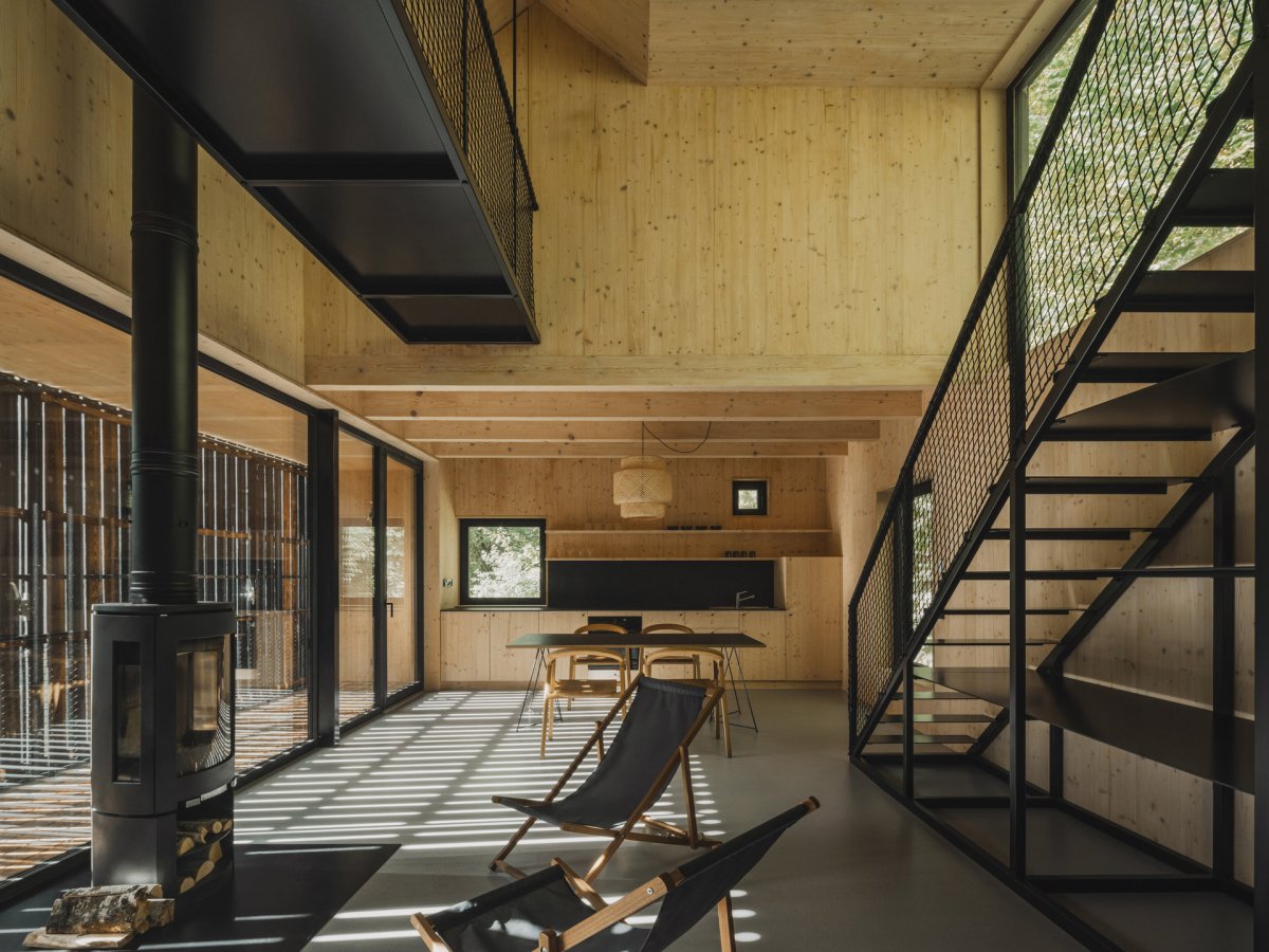 Velkorysý hlavní prostor je možný díky skromným pokojům v patře.  (Chata u Sázavy mezi skálou a řekou; Mimosa Architekti)
