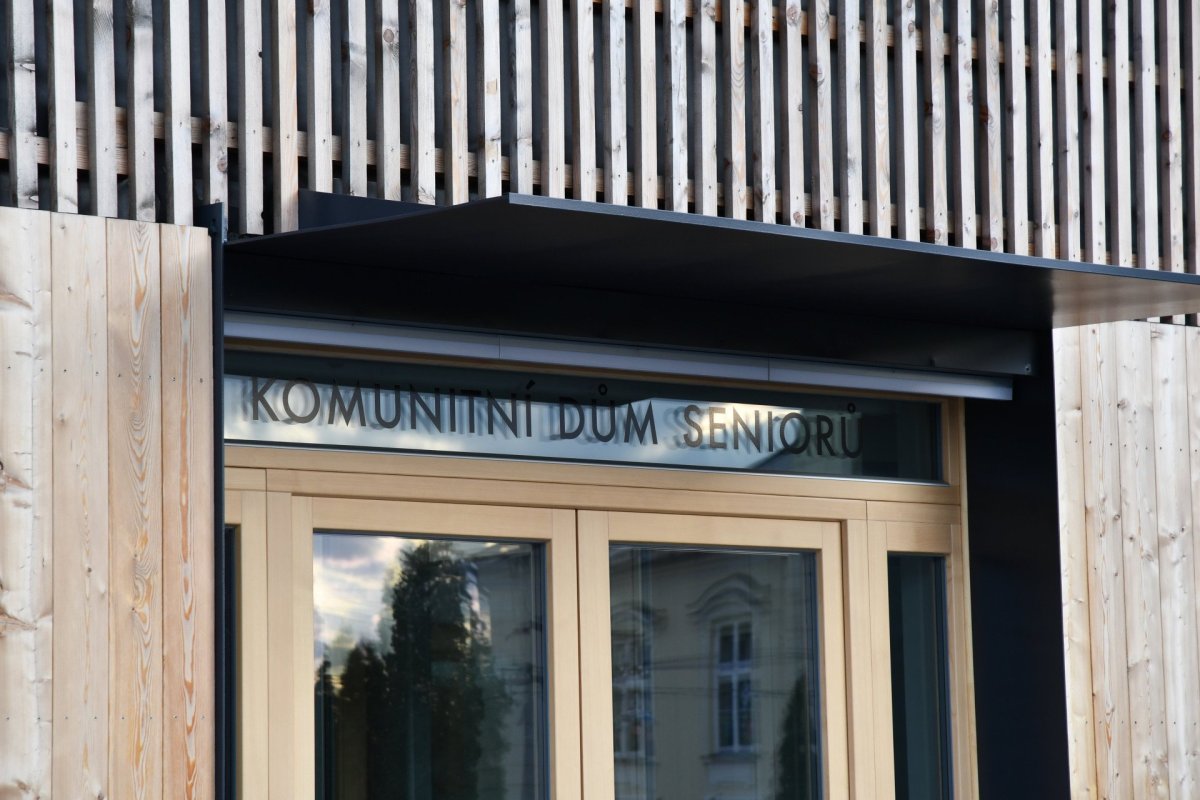 Komunitní dům pro seniory v Holasovicích, City Upgrade: Novostavba je podlouhlá, završuje ji sedlová střecha, fasádní plášť je z modřínových latí