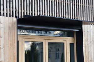 Komunitní dům pro seniory v Holasovicích, City Upgrade: Novostavba je podlouhlá, završuje ji sedlová střecha, fasádní plášť je z modřínových latí