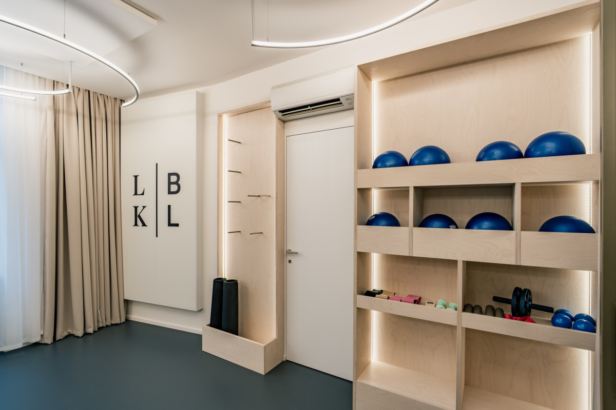 Integrované úložné prostory pro cvičební pomůcky s nepřímým osvětlením pomáhají zachovat vizuální čistotu sálu. (Barre Lab; Barbora Hrtáňová)