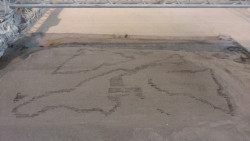 Obr. 21: Detail nasprejování jedné vrstvy písku pojivem při 3D tisku spojováním prášku technologií D-Shape, Itálie / Velká Británie,