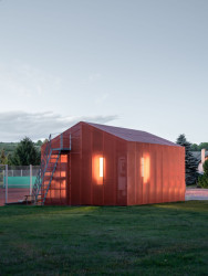 Přes perforovanou plechovou fasádu do něj skoro ani není vidět. (Zázemí tenisového klubu ve Studenci, ateliér CHRAMA)