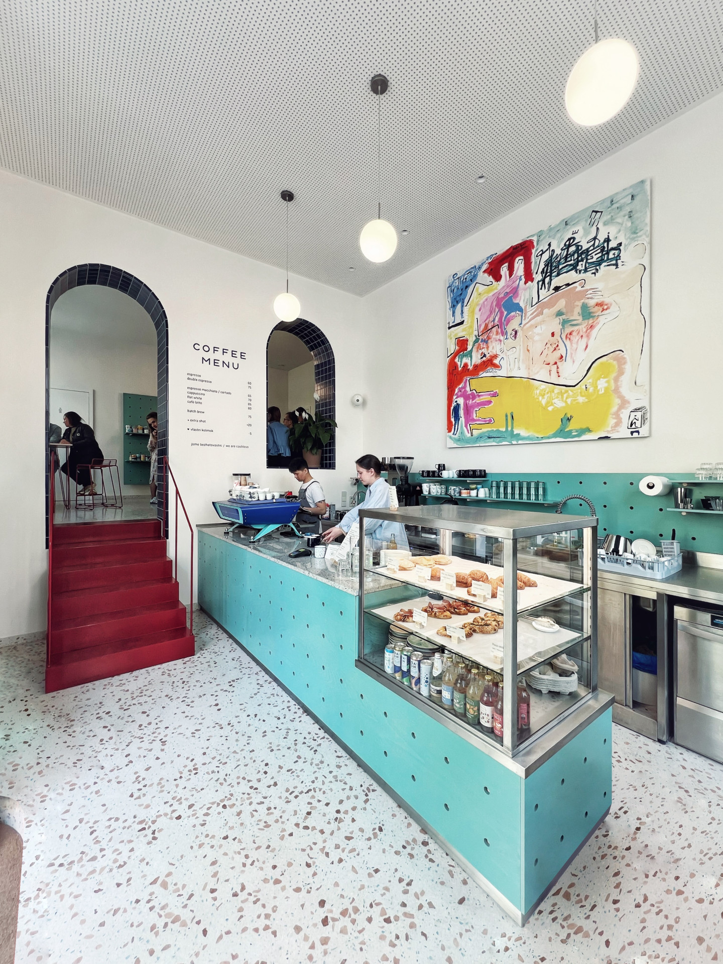 Červené kovové schodiště vyrovnává výškový rozdíl mezi dvěma prostory. (Onesip Coffee, edit!)