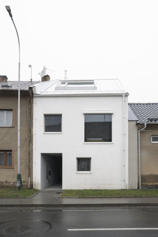 Novostavba je výrazná, svou bílou barvou z fronty tmavých, hlavně šedivých, domů vystupuje. (Rodinný dům v Senici na Hané, TŘI.ČTRNÁCT architekti)