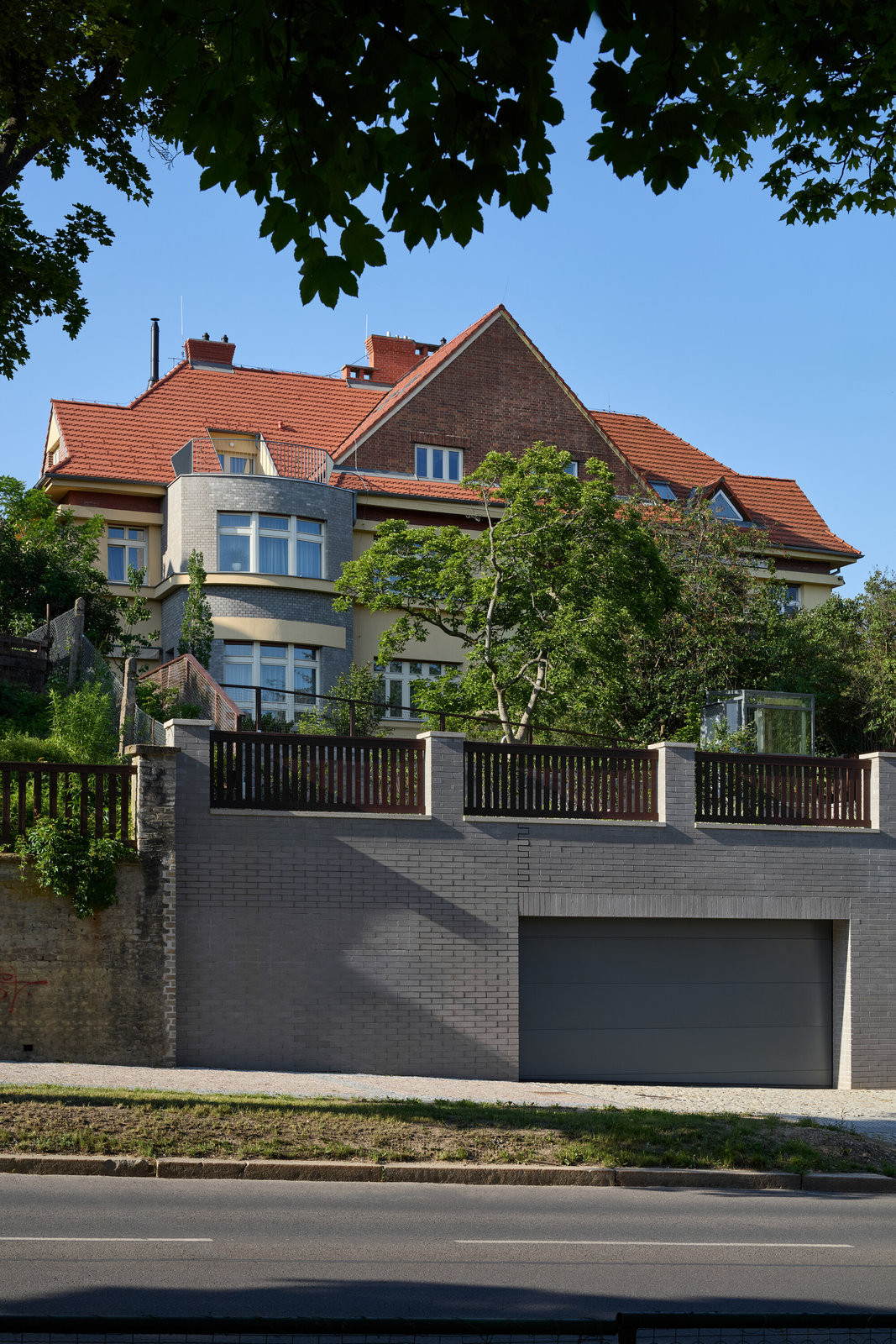 Pohled na novostavbu garáže. Původní garáž zapuštěná v terénním zlomu nevyhovovala staticky ani velikostně, a proto ji nahradila větší železobetonová konstrukce. (Rekonstrukce vily na Vinohradech; Atelier Hajný)