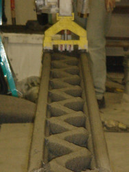 Obr. 11: Ukázka tiskové hlavy a konstrukčního řešení stěny realizované technologií 3D tisku vytlačováním cementové malty systémem Contour Crafting, USA,