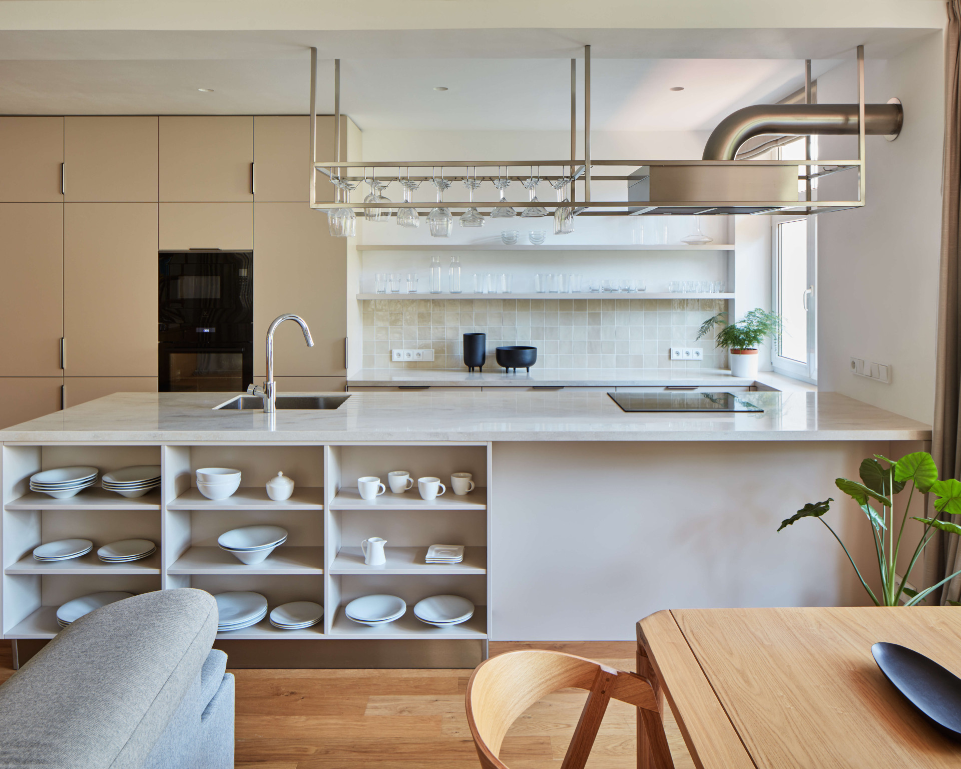 Do vzdušné světlé kuchyně architekti navrhli digestoř zavěšenou na kovové konstrukci, která působí lehce industriálně. (Rekonstrukce bytu ve Strašnicích, MENU architekti)