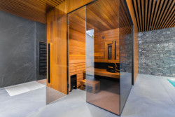 Designová finská sauna TAO v privátním spa disponuje tmavým obkladem, černými doplňky, stěnami zasklenými zatmaveným sklem a zádovým infrapanelem. 