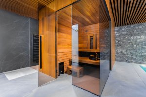 Designová finská sauna TAO v privátním spa disponuje tmavým obkladem, černými doplňky, stěnami zasklenými zatmaveným sklem a zádovým infrapanelem. 