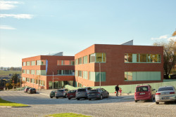 Fasády školy obložené cihelnými pásky a jemně zelené detaily oken či oplocení odkazují na budovu staré hvězdárny. (ZŠ bratří Fričů v Ondřejově; ATELIER 6)