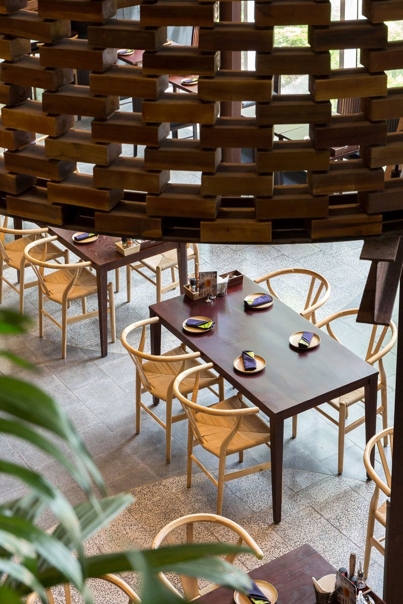 Válce jsou perforované a opticky vymezují soukromí prostor pro posezení u jídla. (Restaurace Pizza 4P’s v Hanoji od česko – vietnamského studia ODDO)