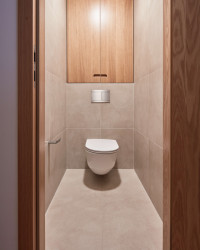 Pro koupelnu zvolili autoři jemné béžové terazzo. Ložnice navazuje na materiály zvolené pro obývací část - dubové dřevo v kombinaci se šedobéžovou. (Rekonstrukce bytu ve Strašnicích, MENU architekti)