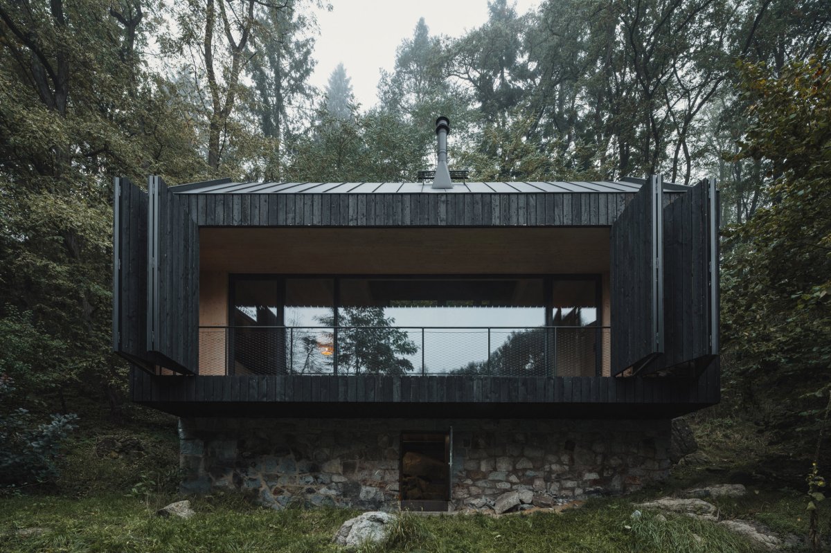 Terasa je chráněná harmonikovou dřevěnou okenicí. (Chata u Sázavy mezi skálou a řekou; Mimosa Architekti)