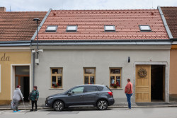 Zvenčí je to řadový dům s průjezdem.