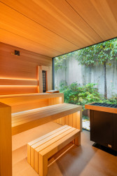 Privátní sauna s hemlockovým obkladem a velkým oknem do zahrady působí vzdušným a otevřeným dojmem. 