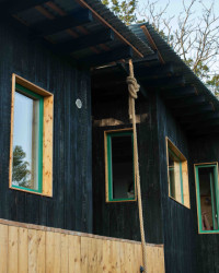 Černou barvu páleného dřeva na fasádě doplňují barevné rámy oken.