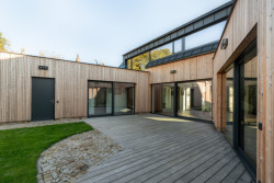 Rodinný dům v Bystřici nad Perštejnem, studio AEIOU: Trojkřídlá struktura svírá vnitřní dvůr, kterým se táhne dřevěná pobytová terasa