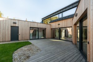 Rodinný dům v Bystřici nad Perštejnem, studio AEIOU: Trojkřídlá struktura svírá vnitřní dvůr, kterým se táhne dřevěná pobytová terasa