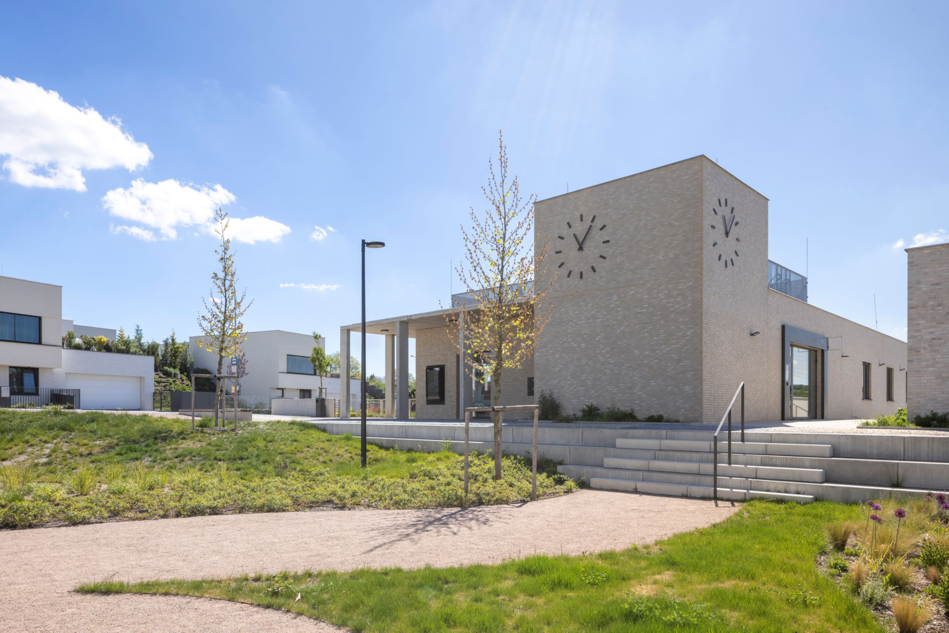 Komunitní centrum s multifunkčním sálem má hodinovou věž. (Obytný soubor Dolina v Lysolajích, knesl kynčl architekti)