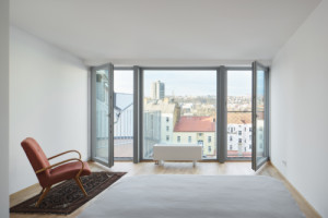 Francouzská okna dvou bytů se otevírají směrem do vnitrobloku. (Nástavba Harfa; matěj šebek architekti)