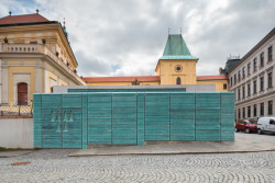 Provoz trafostanice se obrací přímo do ulice, technické zařízení je ale šikovně schované za kovovou konstrukci opláštěnou bronzovými lamelami. (Vstupní objekt do zámeckých sklepů s trafostanicí v Kroměříži od Atelier Štěpán)