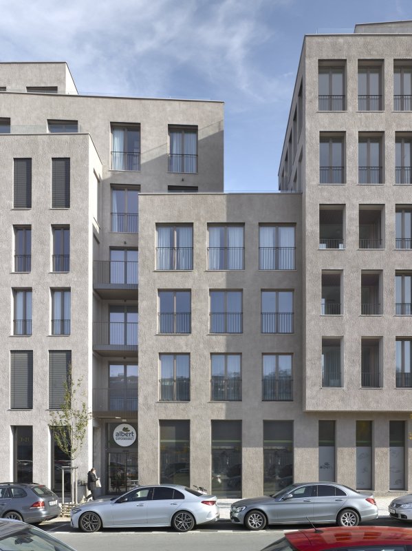 Vertikální formáty oken jsou osazeny v pevných fasádách z hrubé omítky. (Bydlení na brownfieldu smíchovského nádraží; Chalupa architekti a partneři)