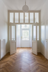 Tato stěna v chodbě je nová, svou koncepcí ale navazuje na původní dveře a okna. (Rekonstrukce bytu v Praze, BY architects)