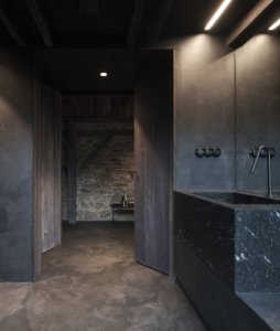 Dominantním materiálem interiéru se stala černá masivní žula použitá například v koupelně nebo na barovém pultu. (Chalupa na Vysočině; Plus One Architects)