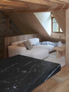Společenskou část podkroví doplňuje barový pult z černé masivní žuly. (Chalupa na Vysočině; Plus One Architects)