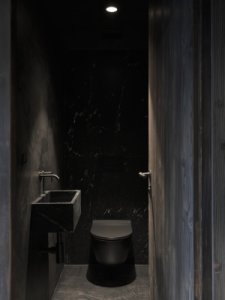 Dominantním materiálem interiéru se stala černá masivní žula použitá například v koupelně nebo na barovém pultu. (Chalupa na Vysočině; Plus One Architects)
