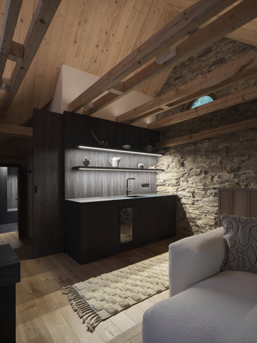 Interiér podkroví pracuje se syrovými materiály, tlumeným světlem a přiznanými konstrukcemi. (Chalupa na Vysočině; Plus One Architects)