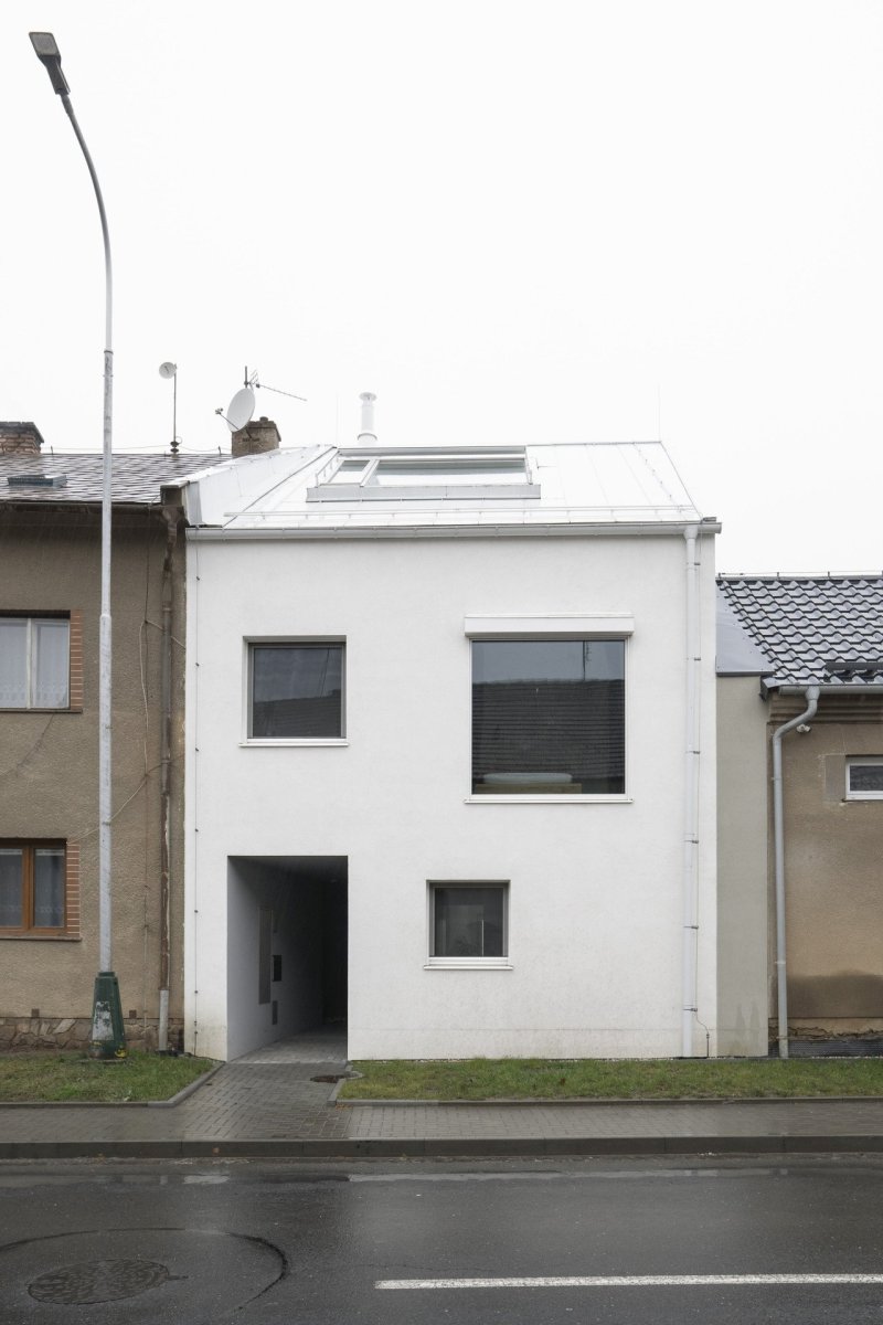 Novostavba je výrazná, svou bílou barvou z fronty tmavých, hlavně šedivých, domů vystupuje. (Rodinný dům v Senici na Hané, TŘI.ČTRNÁCT architekti)