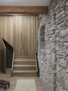 Posuvné dveře svou hranou citlivě kopírují nerovný povrch původní kamenné stěny. (Chalupa na Vysočině; Plus One Architects)
